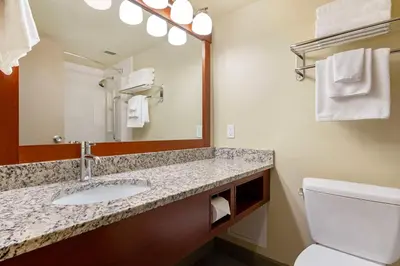 a bathroom with a sink and a mirror and a toilet at Best Western Plus Barclay Hotel in Port Alberni
