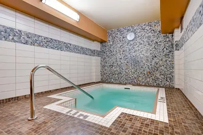 a hot tub in a bathroom with a tile wall at Best Western Plus Barclay Hotel in Port Alberni