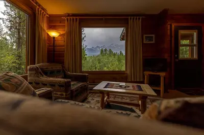 a living room with a table and chairs and a window at Mica Mountain Lodge & Log Cabins in Tete Jaune Cache