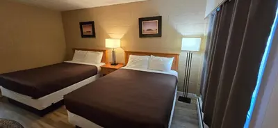 a hotel room with two beds and two lamps at Flamingo Motel in Penticton