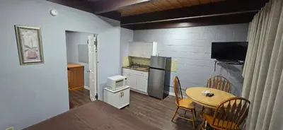 a kitchen and dining room with a table and a small kitchen at Flamingo Motel in Penticton