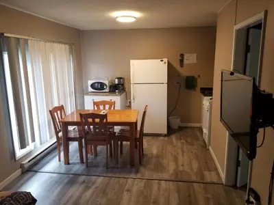 a kitchen with a table and chairs and a refrigerator at Apple Tree Inn in Penticton