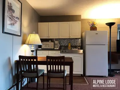 a kitchen with a table and a refrigerator at Alpine Lodge Motel & Restaurant in Grande Cache