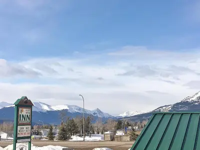 a sign in the snow with mountains in the background at Alpine Lodge Motel & Restaurant in Grande Cache