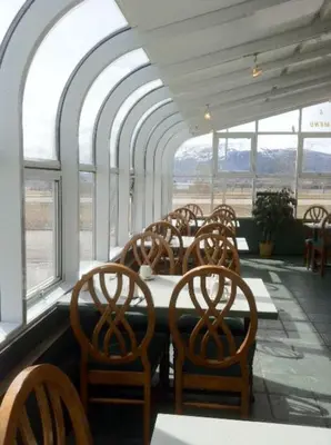 a dining room with chairs and tables and windows at Alpine Lodge Motel & Restaurant in Grande Cache