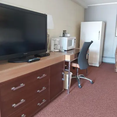 a room with a desk with a television and a chair at Alpine Lodge Motel & Restaurant in Grande Cache