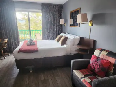 a hotel room with a large bed and a chair at Motel Tyrol in Radium Hot Springs