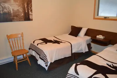 a hotel room with two beds and a chair at Motel Tyrol in Radium Hot Springs