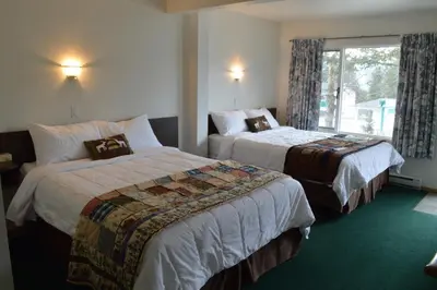 a hotel room with two beds and a window at Motel Tyrol in Radium Hot Springs