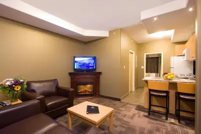 a living room with a fireplace and a tv at Woodlands Inn & Suites in Fort Nelson