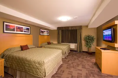 a hotel room with two beds and a flat screen tv at Woodlands Inn & Suites in Fort Nelson