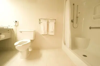 a white bathroom with a toilet and a shower at Woodlands Inn & Suites in Fort Nelson
