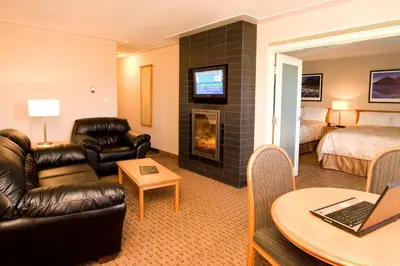 a hotel room with a living room with a fireplace at Woodlands Inn & Suites in Fort Nelson