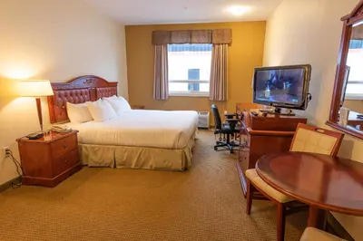 a hotel room with a bed and a table and a television at Days Inn by Wyndham Bonnyville in Bonnyville