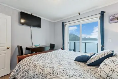 a bedroom with a bed with a view of the water at The Oceanfront Inn on Stephens Bay in Coal Harbour