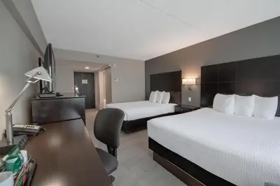 a hotel room with two beds and a desk at Coast Nisku Inn & Conference Centre in Nisku