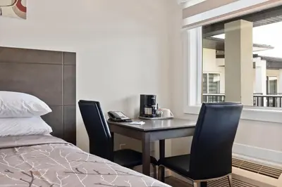 a bedroom with a desk with two chairs and a bed at Oasis Inn in Kelowna