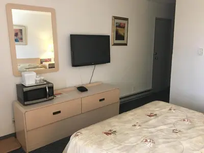 a bedroom with a dresser with a television on the wall at DC Lodge in Dawson Creek