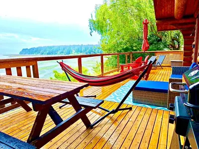 a deck with a wooden table and a hammock on it at The Beach House Texada - Gillies Bay Favourite Cabin in Gillies Bay