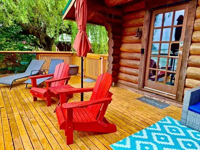 a porch with three red chairs and an umbrella at The Beach House Texada - Gillies Bay Favourite Cabin in Gillies Bay