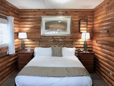 a bedroom with wooden walls and a bed with two lamps at Rockwater Secret Cove Resort in Sechelt