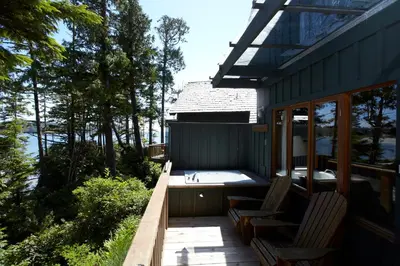 a porch with two chairs and a tub on a house at Middle Beach Lodge in Tofino