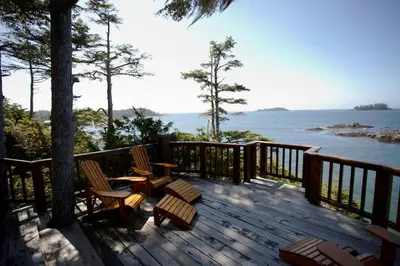 a deck with chairs and tables and a view of the water at Middle Beach Lodge in Tofino