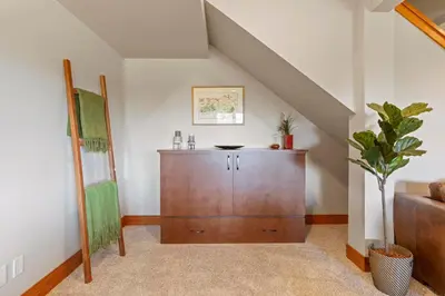 a living room with a wooden cabinet and a staircase at Shawnigan Hills Guest Suite in Shawnigan Lake