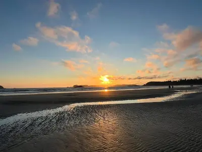 a sunset on a beach with the sun setting at Seafarer Bed & Breakfast in Tofino