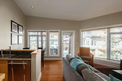 a living room with a couch and a kitchen at Cox Bay Beach Resort in Tofino