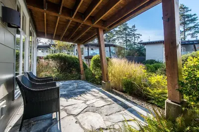a patio with two chairs under a wooden pergola at Cox Bay Beach Resort in Tofino