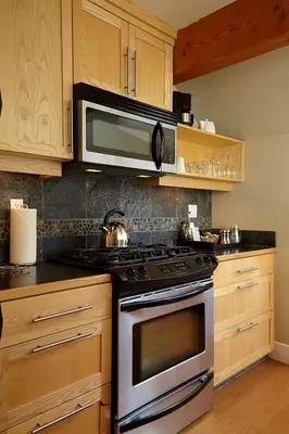 a kitchen with a stove and a microwave at Cox Bay Beach Resort in Tofino