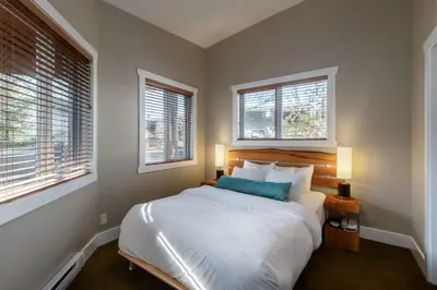 a bedroom with a large bed with two windows at Cox Bay Beach Resort in Tofino