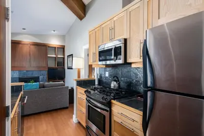 a kitchen with a stainless steel refrigerator and wooden cabinets at Cox Bay Beach Resort in Tofino