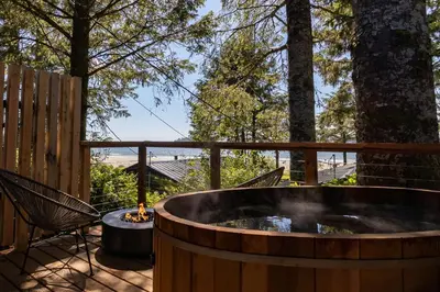 a hot tub on a deck with a table and chairs at Mackenzie Beach Resort in Tofino