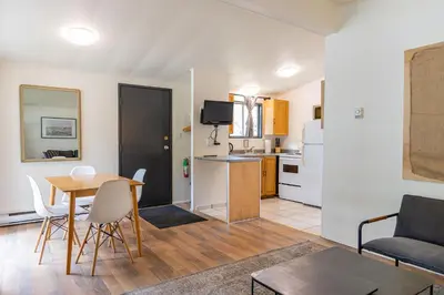 a living room with a table and a kitchen at Mackenzie Beach Resort in Tofino