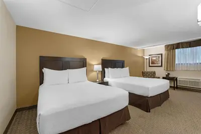 a hotel room with two beds and a desk at Best Western Plus Baker Street Inn in Nelson