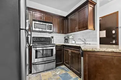 a kitchen with wooden cabinets and stainless steel appliances at The Mountaineer by InstantSuites Pool & HotTub in Canmore