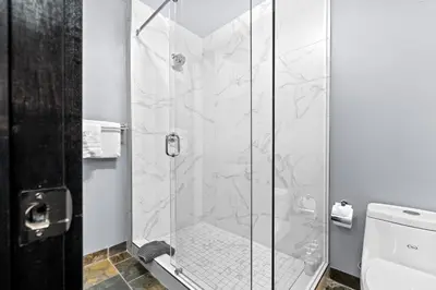 a shower with a glass door in a bathroom at The Mountaineer by InstantSuites Pool & HotTub in Canmore