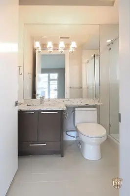 a bathroom with a toilet and a sink and a mirror at The Chateau in Burnaby