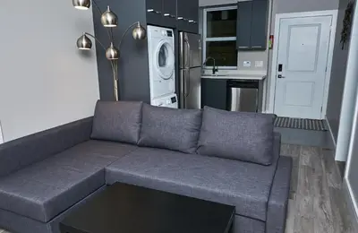 a living room with a couch and a kitchen at The Chateau in Burnaby