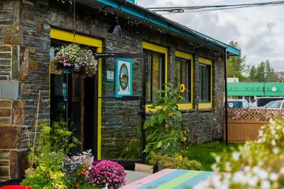 a brick building with a yellow front door and flowers at Dreamcatcher Hostel in Golden