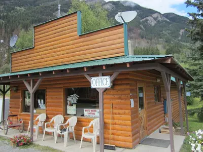 a small building with white chairs in front of it at Mount Robson Lodge in Mount Robson