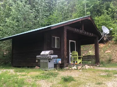 a small cabin with a stove and a chair at Noah's Ark Campground in Revelstoke