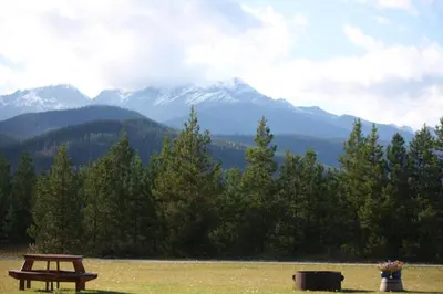 a picnic table in a field with mountains in the background at Twin Peaks Resort in Valemount