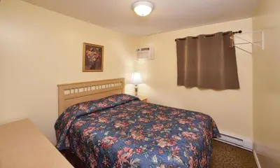 a bedroom with a bed and a lamp and a table at Black Sea Motel in Penticton