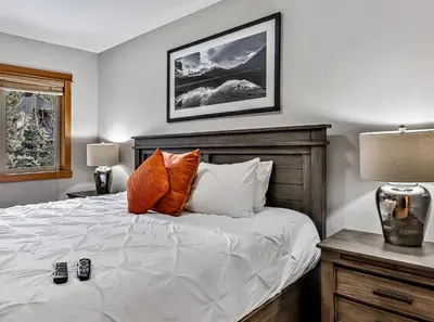 a bedroom with a bed with orange and white pillows at Suites with Pool & Hot tubs managed by Little Sister Getaways in Canmore