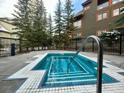 a swimming pool with a metal rail next to a building at Suites with Pool & Hot tubs managed by Little Sister Getaways in Canmore