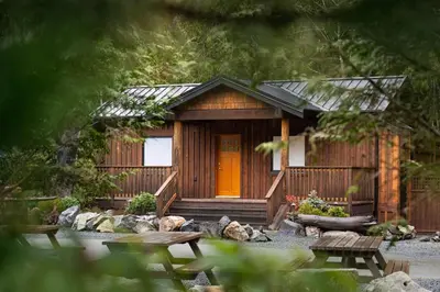 a small wooden cabin with a orange door at West Coast Trail Lodge in Port Renfrew