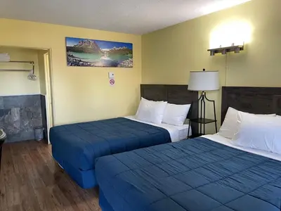 two beds in a hotel room with blue sheets at Port-O-Call Inn in Nanaimo